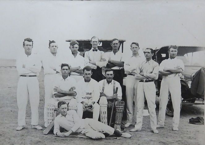 Group of people posing in front of a car in a black-and-white outdoor photo