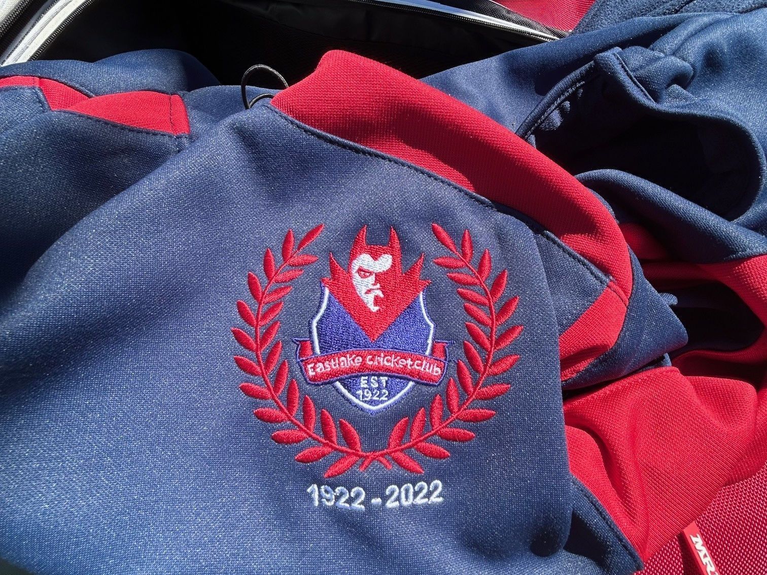 Blue and red embroidered fabric with a crest and “1922–2022” text