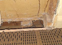 There is a hole in the wall next to a carpet.