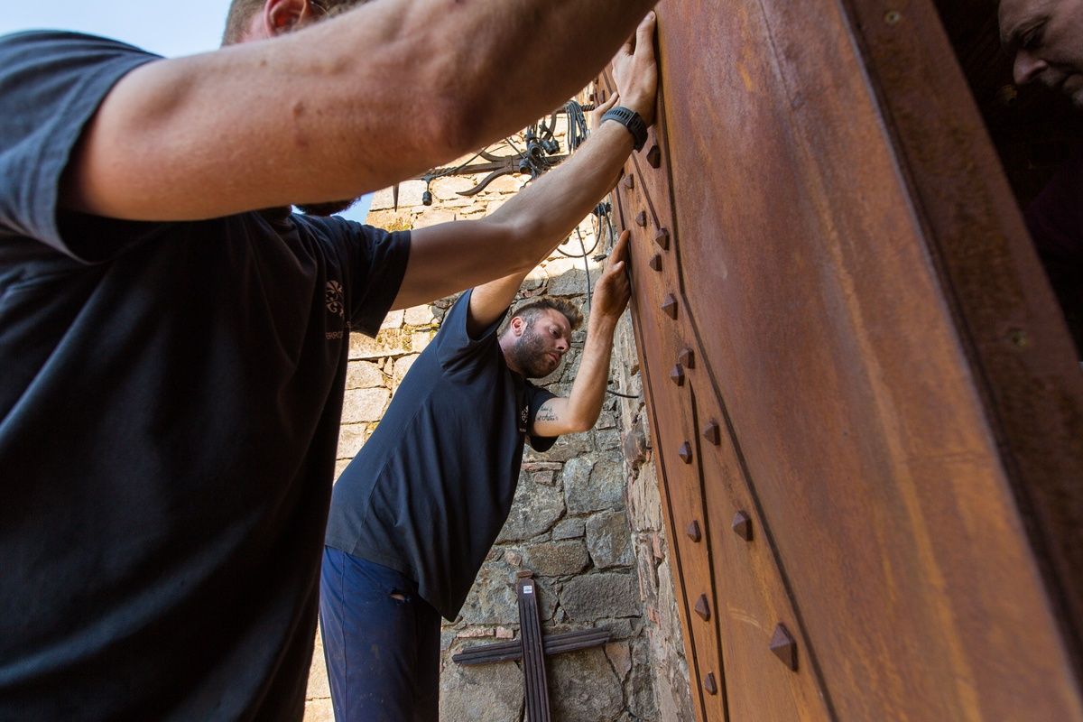 Craftsmen installing a large wooden castle door.