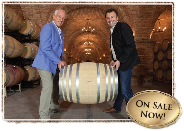 Two men holding a wooden barrel in a wine cellar. 