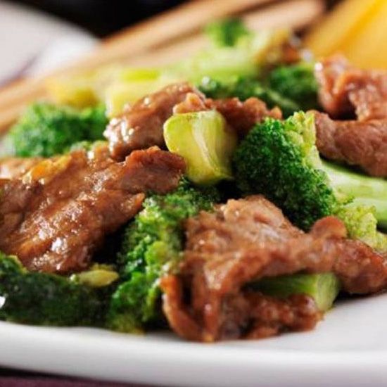Beef and broccoli stir-fry with chopsticks. Green broccoli and brown beef in a sauce.