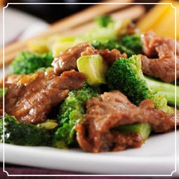 Beef and broccoli stir-fry on a white plate, with wooden chopsticks.