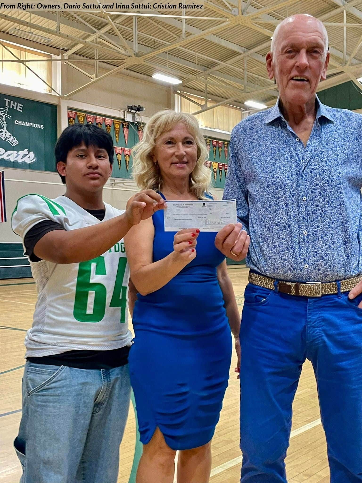 Three people holding a check in a gymnasium. The check is being presented, with two smiling.