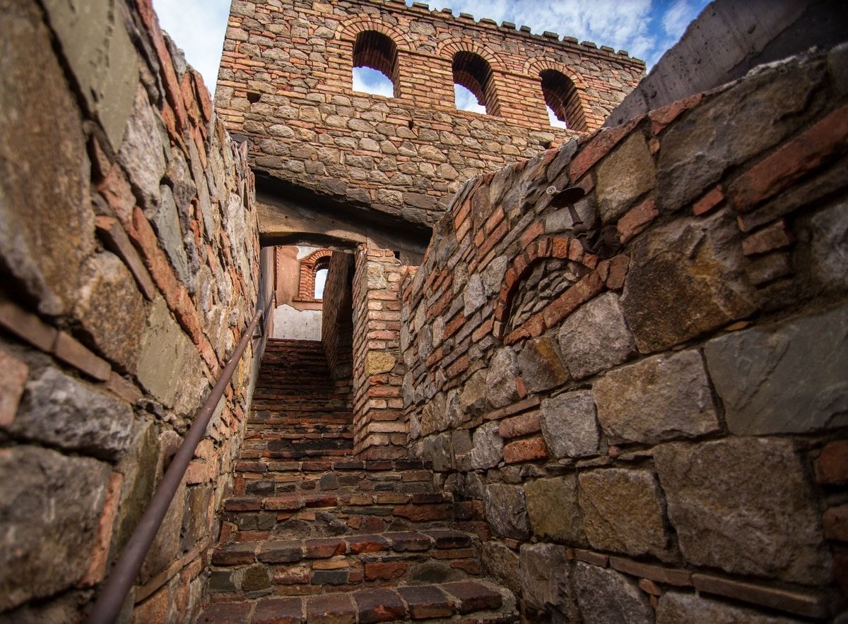 Stone steps leading up to an arched doorway within a brick and stone castle structure.