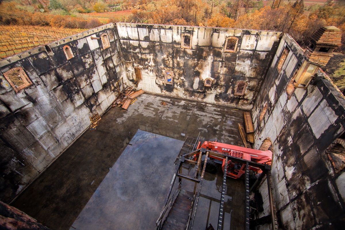 Interior of a weathered concrete structure. Water on floor, rusted equipment, small window openings.