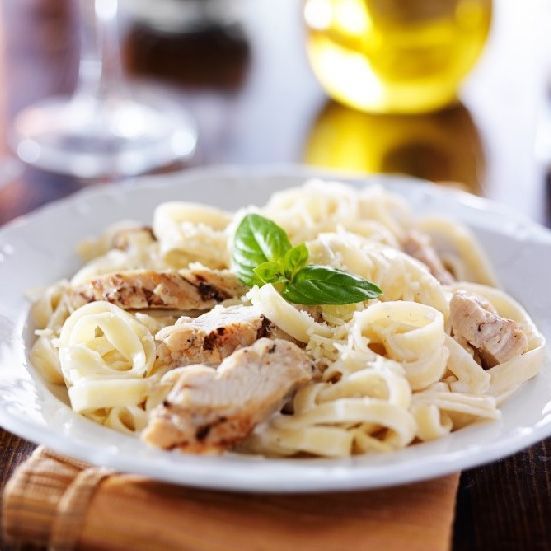 Chicken Alfredo pasta with basil garnish.