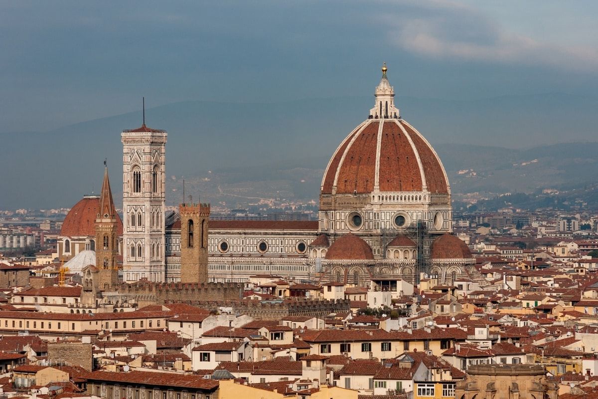 Florence, Italy cityscape with the Duomo and Giotto's Campanile, terracotta roofs, and a clear sky.