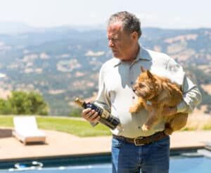Greg Melanson holding a bottle of wine with a small dog.