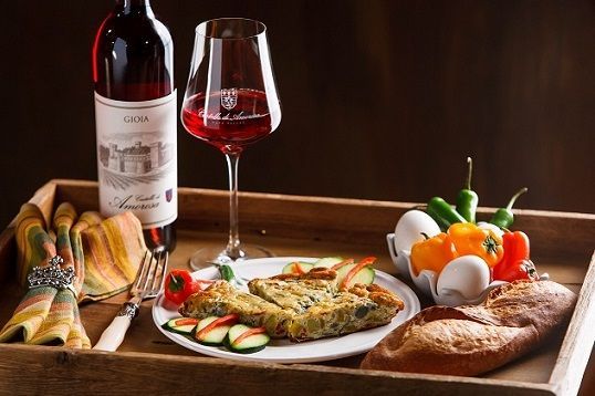 Wine, frittata, vegetables, and bread on a serving table