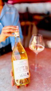 Person holding a bottle of Libero Moscato with a filled wine glass nearby.