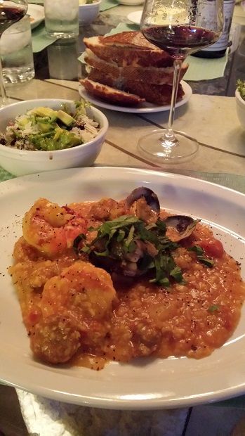 Seafood risotto with bread and red wine on table