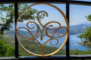 Gold monogram on a vineyard gate overlooking hills and water.
