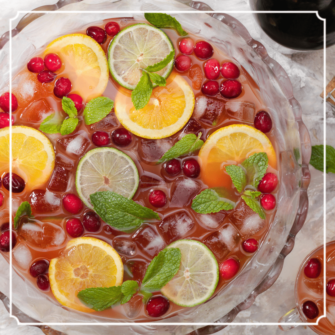 Punch bowl filled with ice, cranberries, citrus slices, and mint.