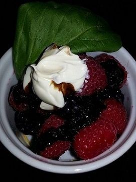 Berries topped with cream and balsamic glaze.