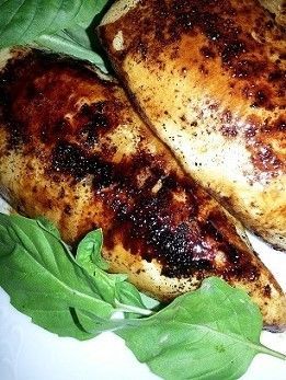 Cooked chicken breast with a browned crust on greens.