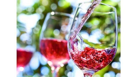 Wine being poured into a glass outdoors with other glasses in the background