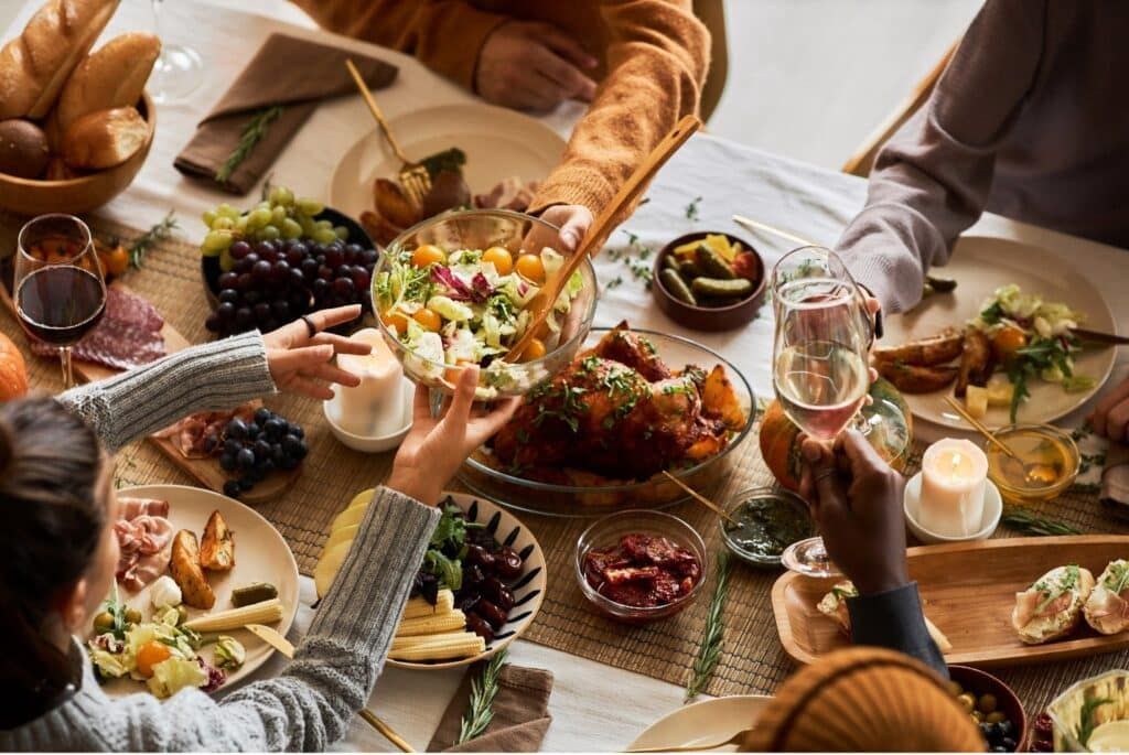 People sharing food around a table with wine glasses.
