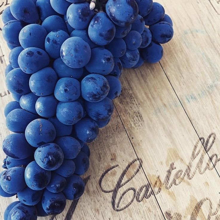 Bunch of blue grapes on a wooden surface with a faded 