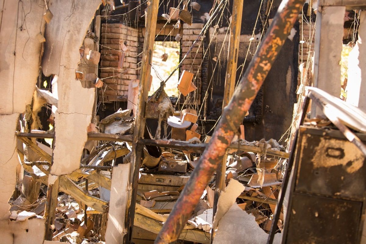 Interior view of a burnt structure; exposed wood and brick with debris.