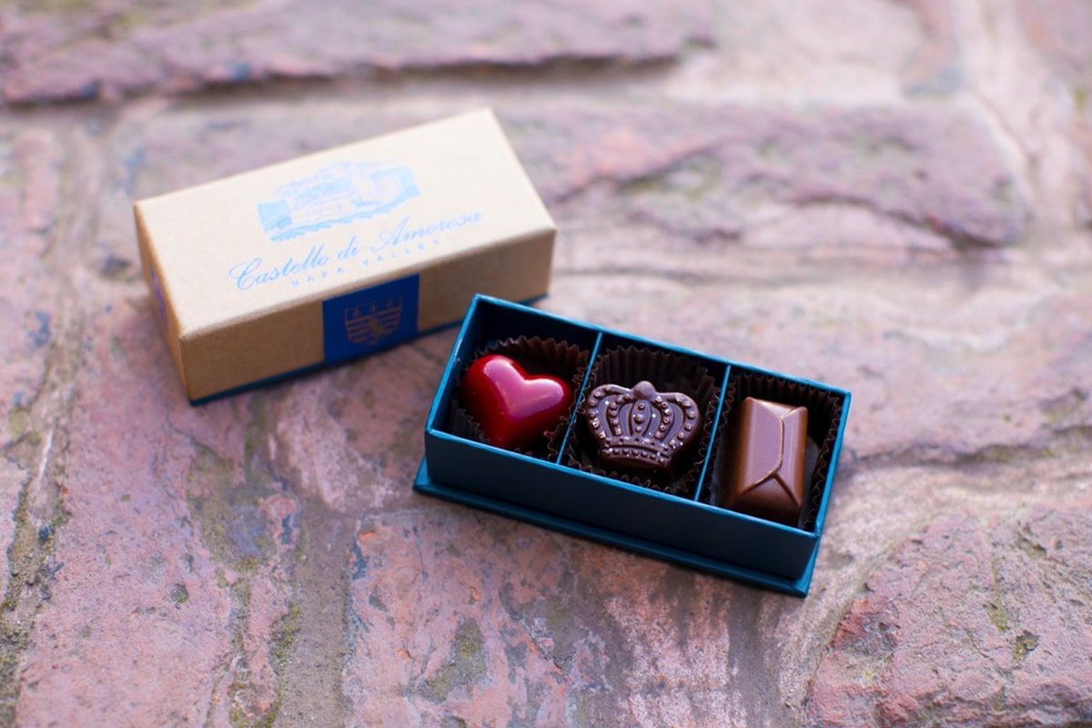 Box of chocolates with heart, crown, and rectangular shapes, on brick surface.