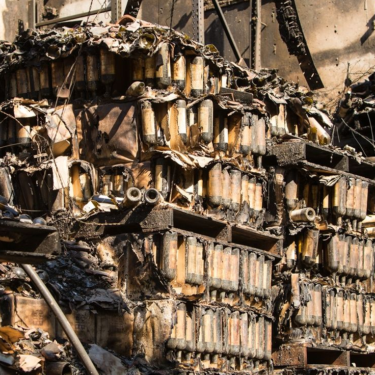 Charred, burnt structure with stacks of cylindrical objects.