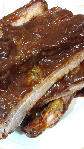 BBQ ribs coated in sauce stacked on a plate