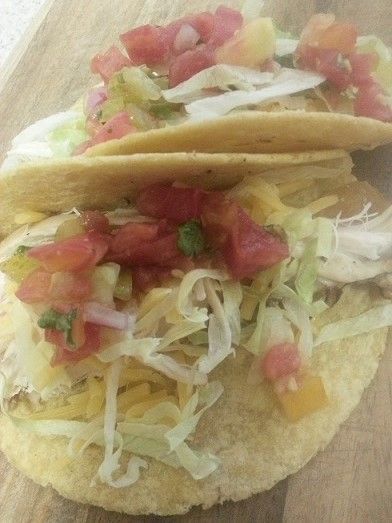 Two tacos filled with lettuce, cheese, and salsa on a wooden surface