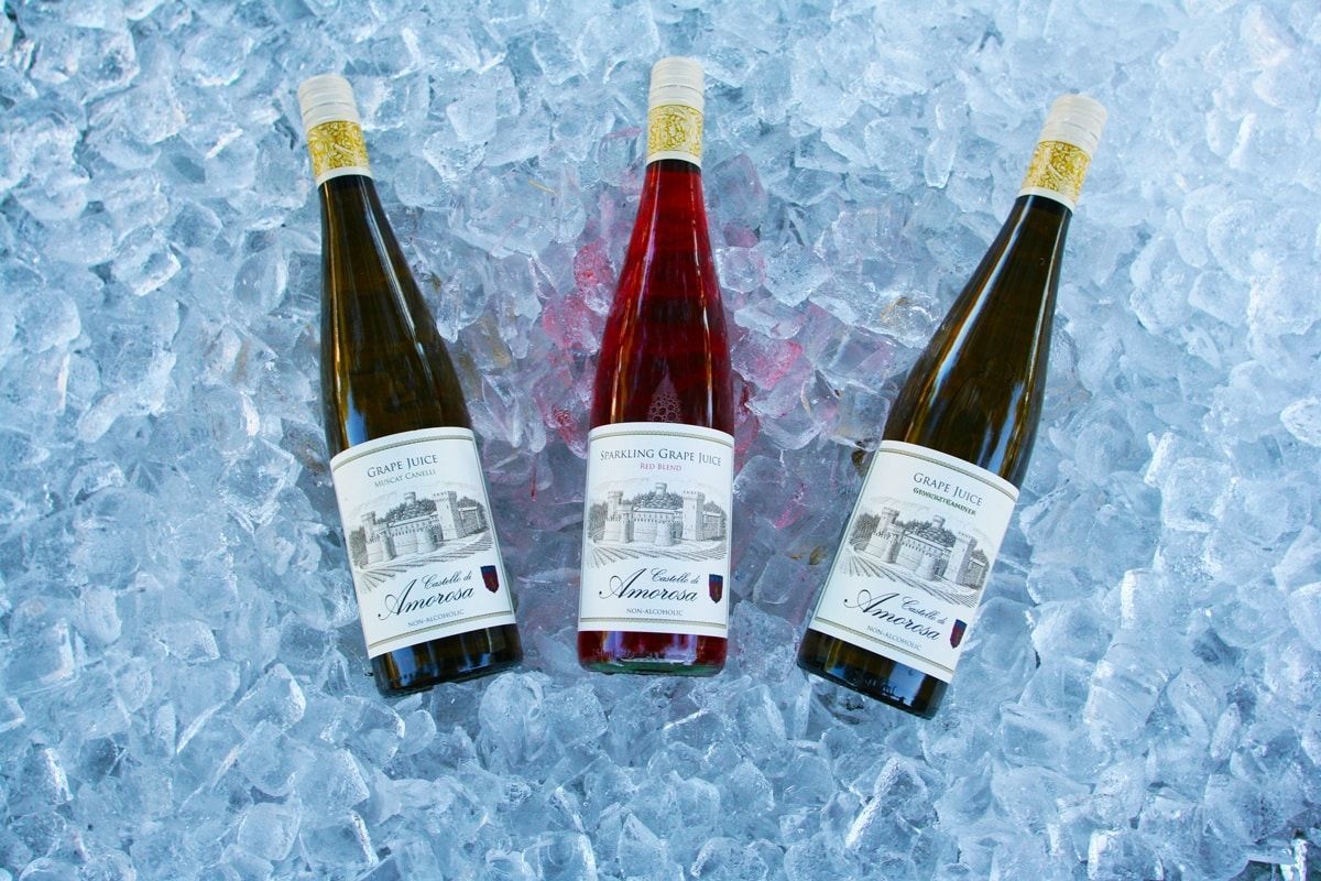 Three wine bottles, one red and two white, chilled in ice.