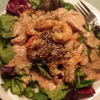 Shrimp salad with greens and creamy dressing topped with sesame seeds