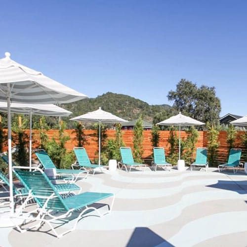Poolside with lounge chairs and umbrellas under a sunny sky.