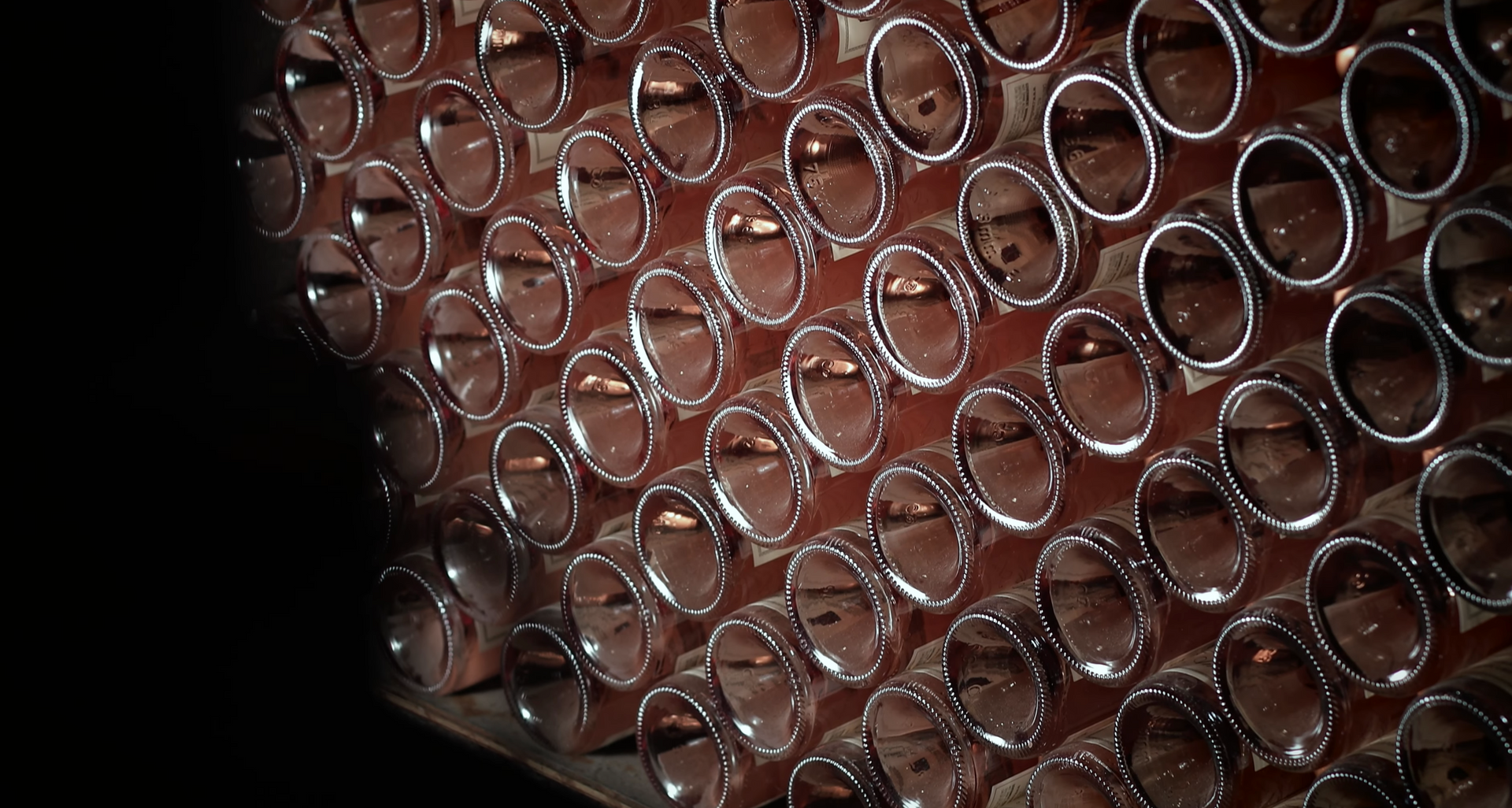 Rows of dark, reflective tubes in a close-up shot, arranged on a wooden structure.