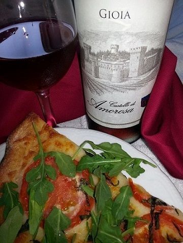 Pizza slice with arugula and wine