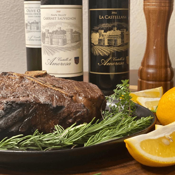 Roasted meat platter with wine bottles, rosemary, lemons, and pepper grinder.