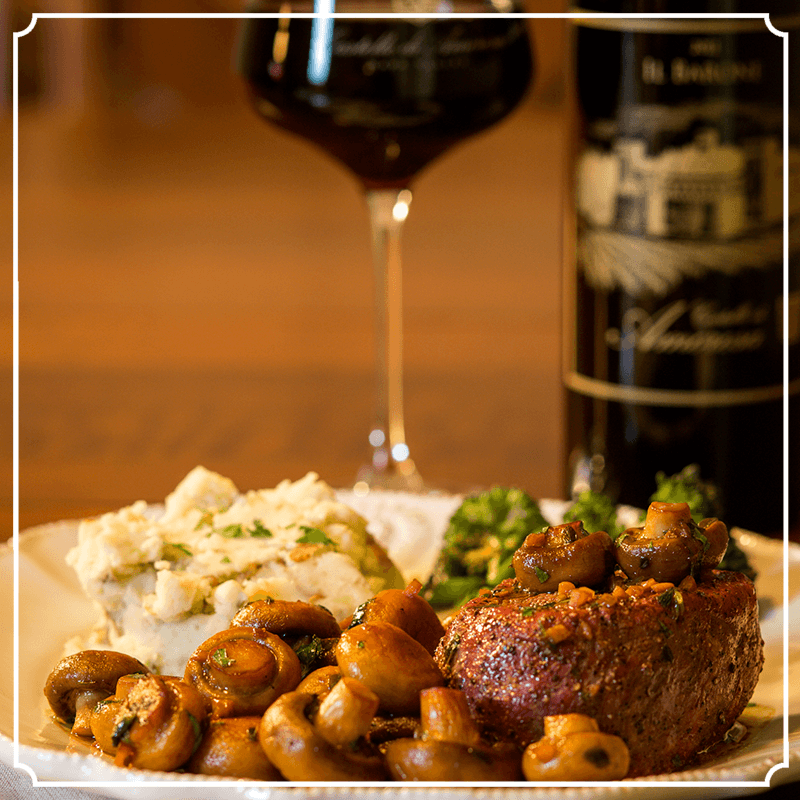 Steak dinner with mashed potatoes, mushrooms, and wine.