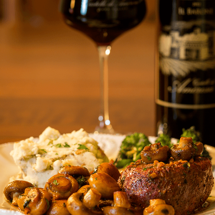 Steak with mushrooms, mashed potatoes, and broccoli, paired with red wine.