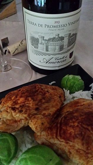 Plate of chicken and rice with glass and bottle of red wine