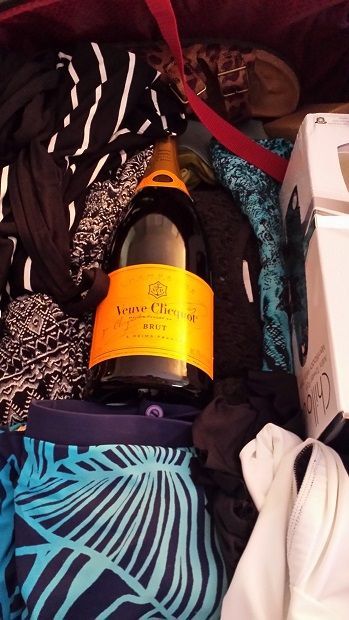 Champagne bottle packed in suitcase among clothes