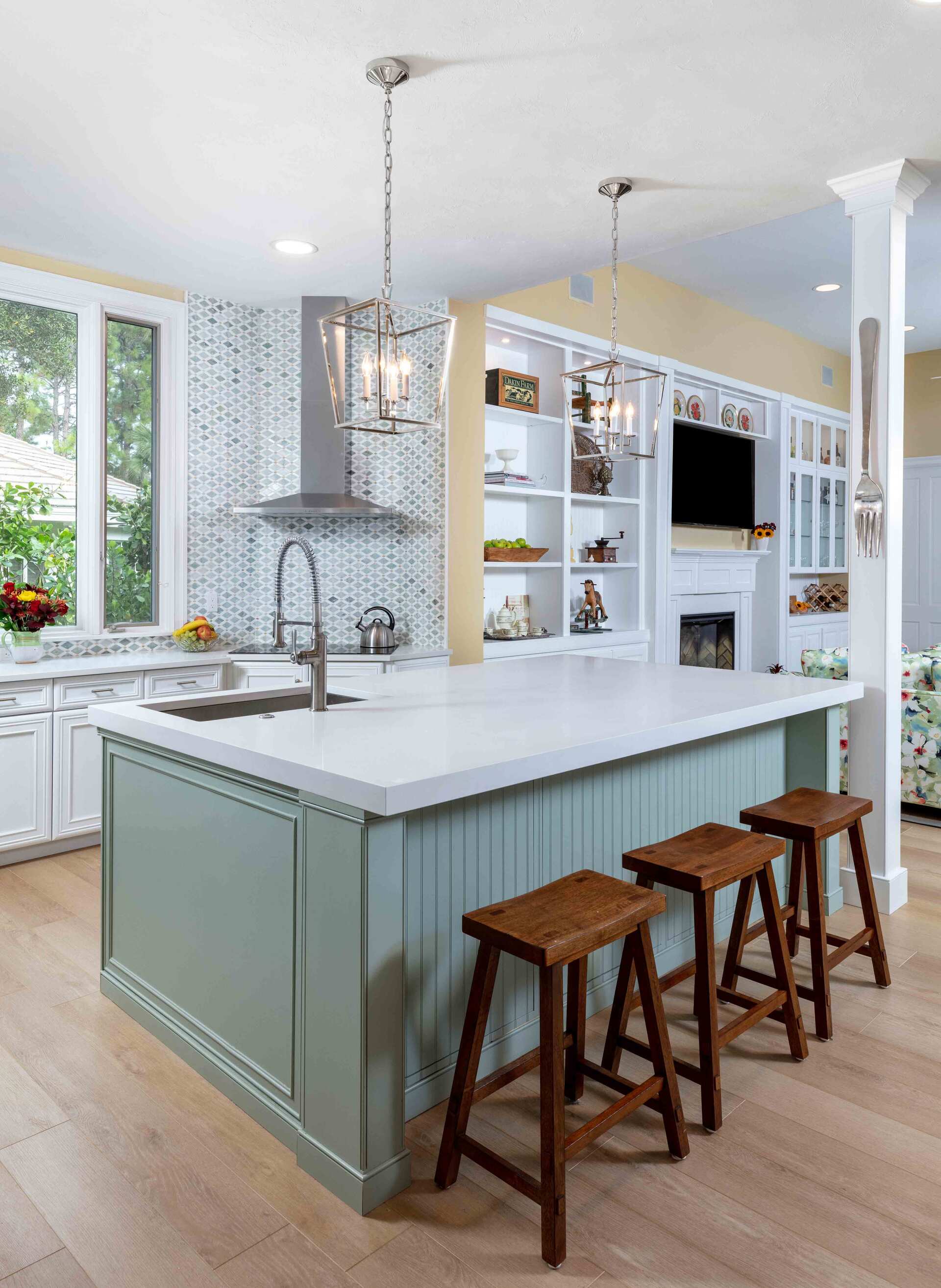 A kitchen with a large island and stools in it.
