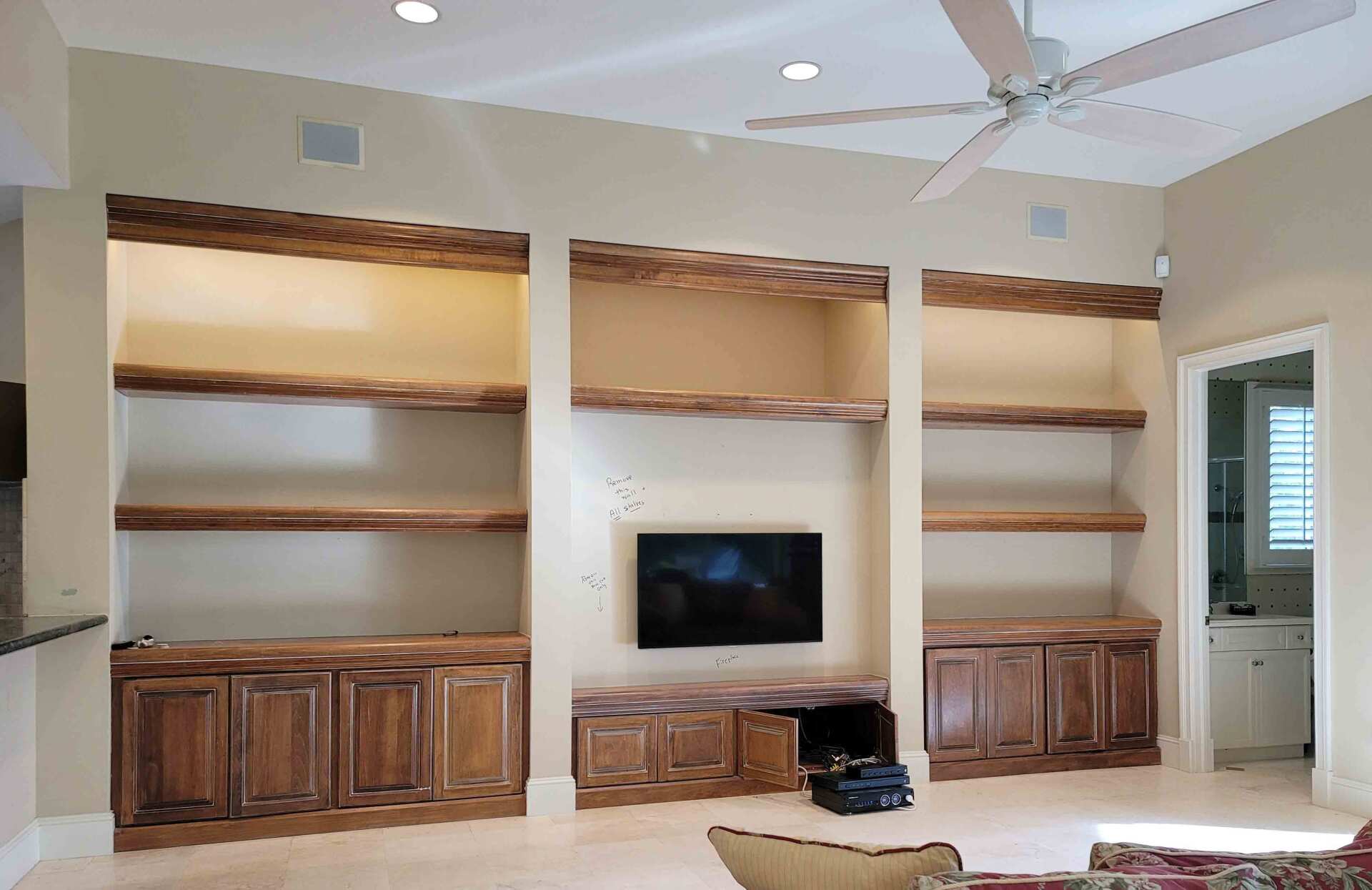 A living room with a ceiling fan and a flat screen tv on the wall.