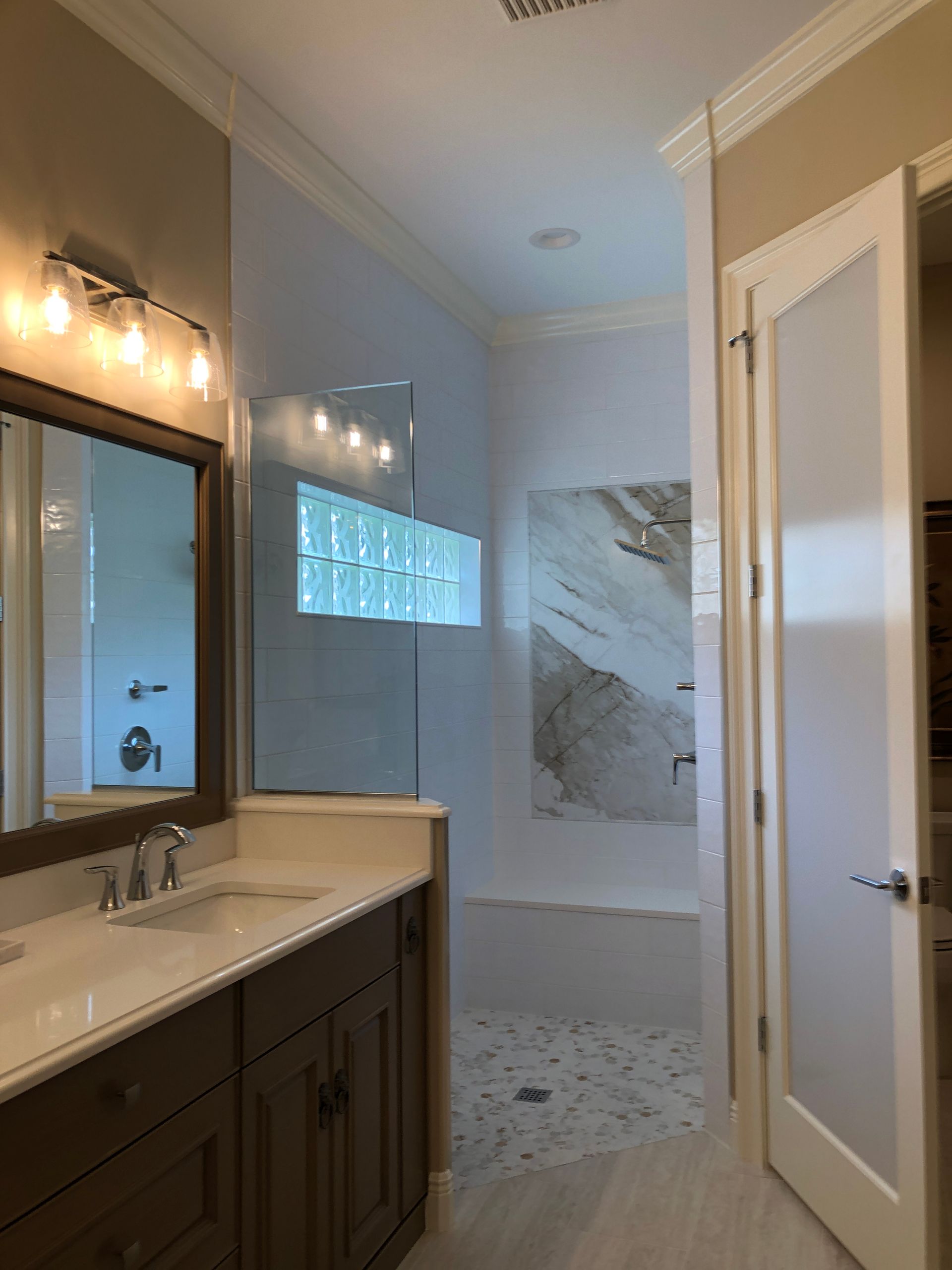 A bathroom with a sink, mirror and walk in shower.