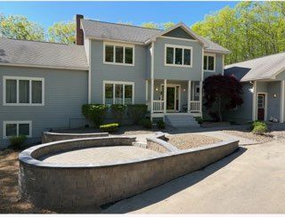 Modern gray house with a curved stone fountain in the front yard