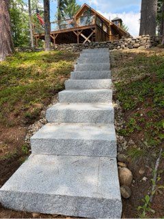 Steep concrete stairs leading up a wooded hillside to a cabin with a wooden deck
