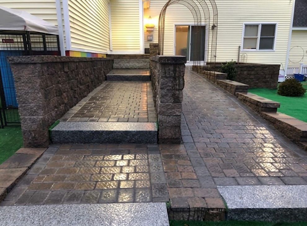 Stone-wall-lined backyard with freshly built natural stone patio in Maine