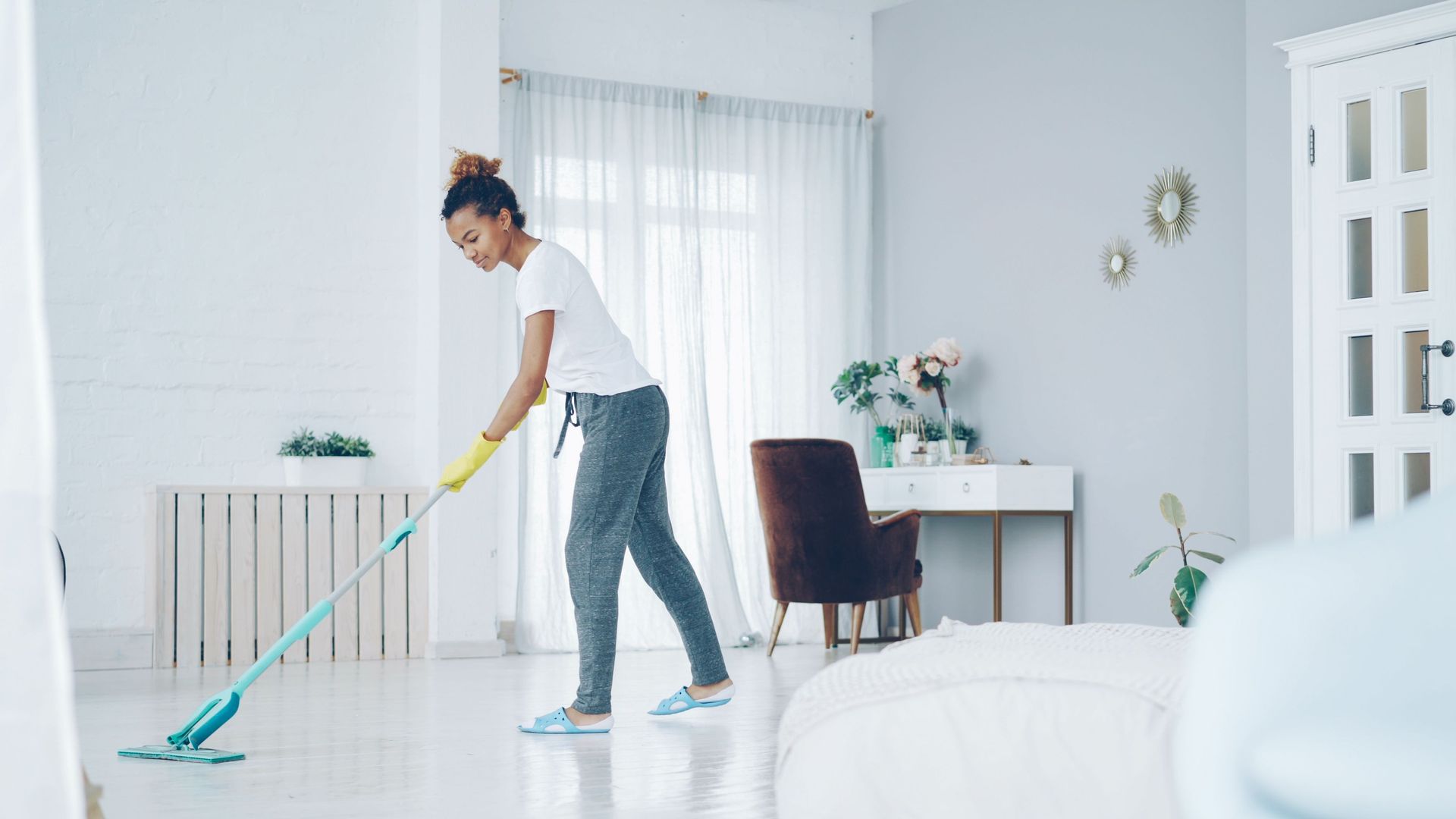 Person mopping a bright white living room with a turquoise mop