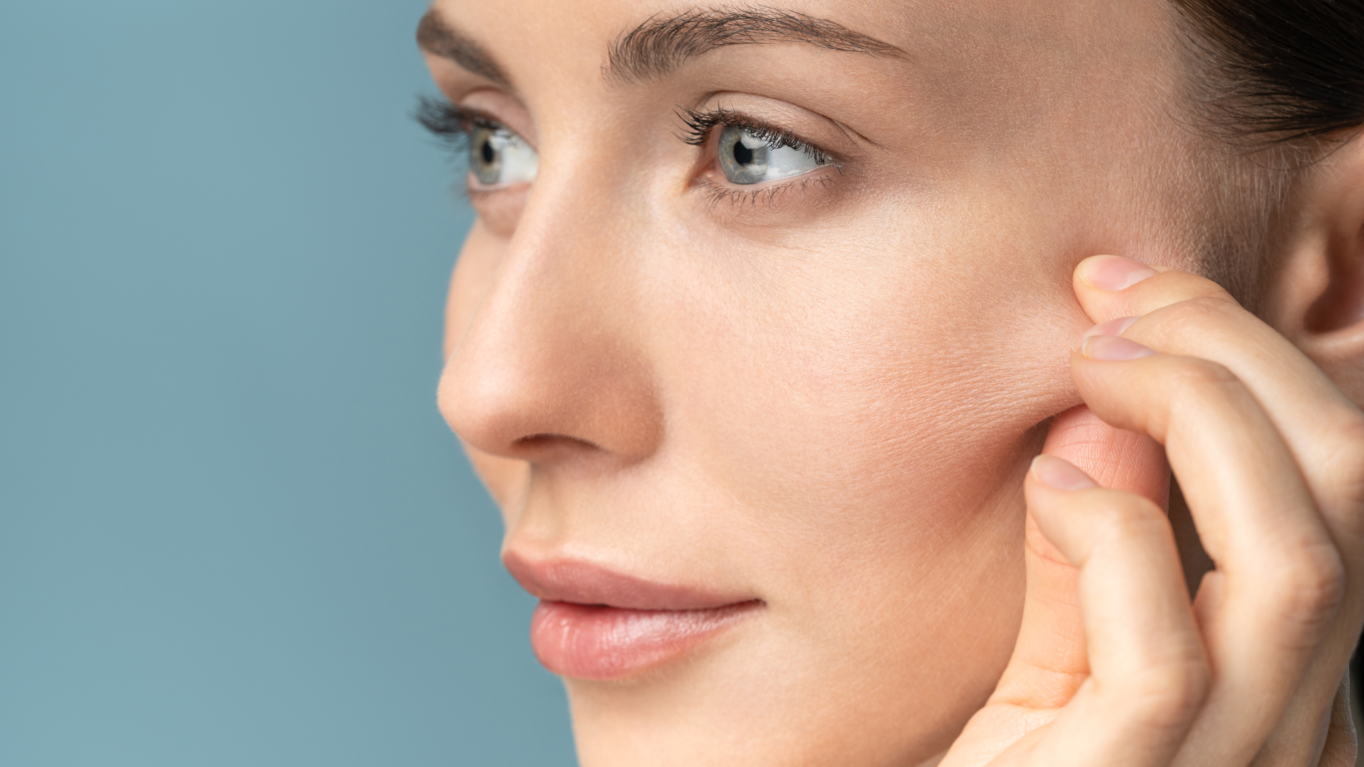 Woman pinching the loose skin from cheeks, preparing for face threading