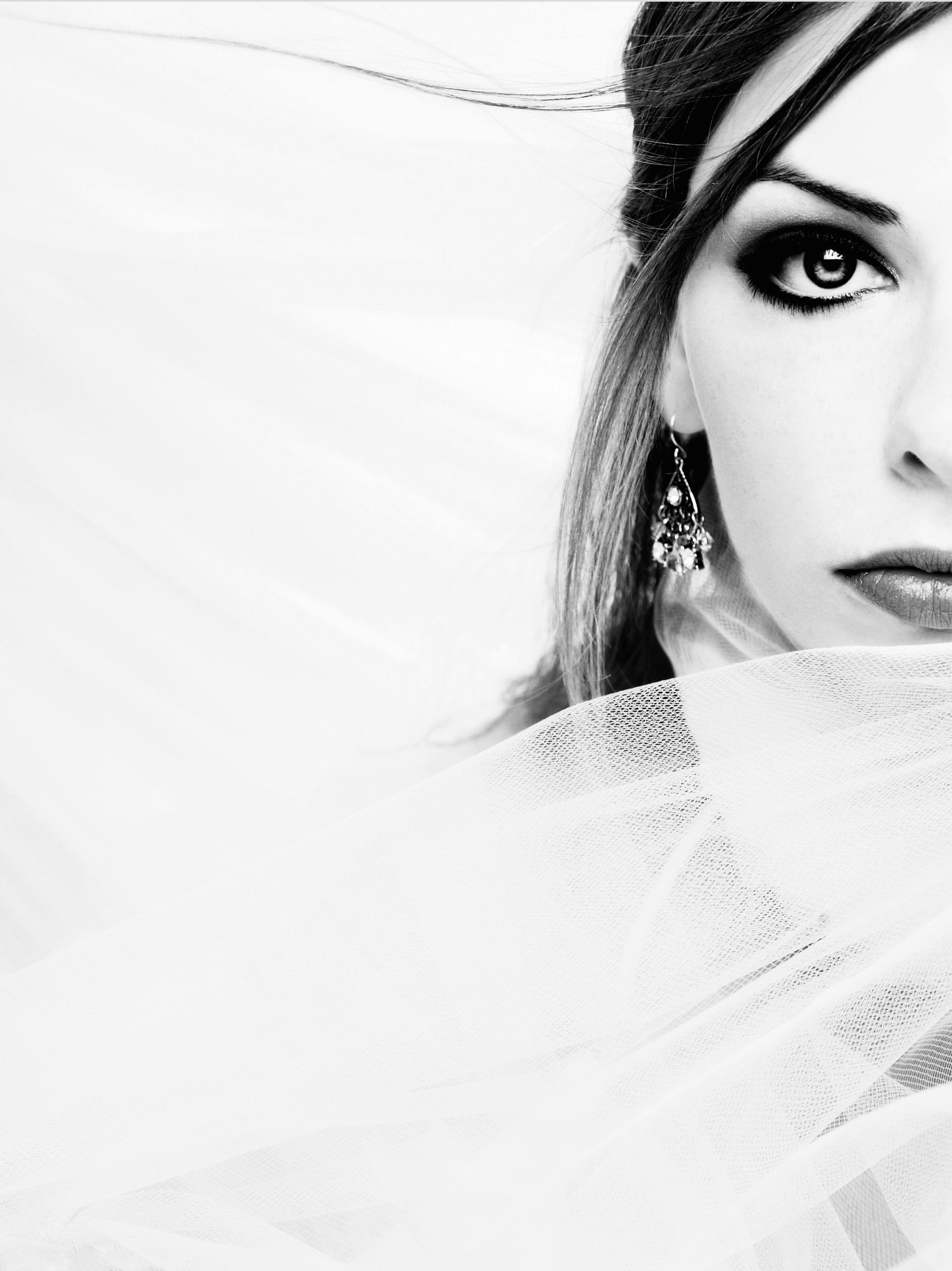 Black-and-white close-up of a woman’s face partially veiled by a sheer white fabric