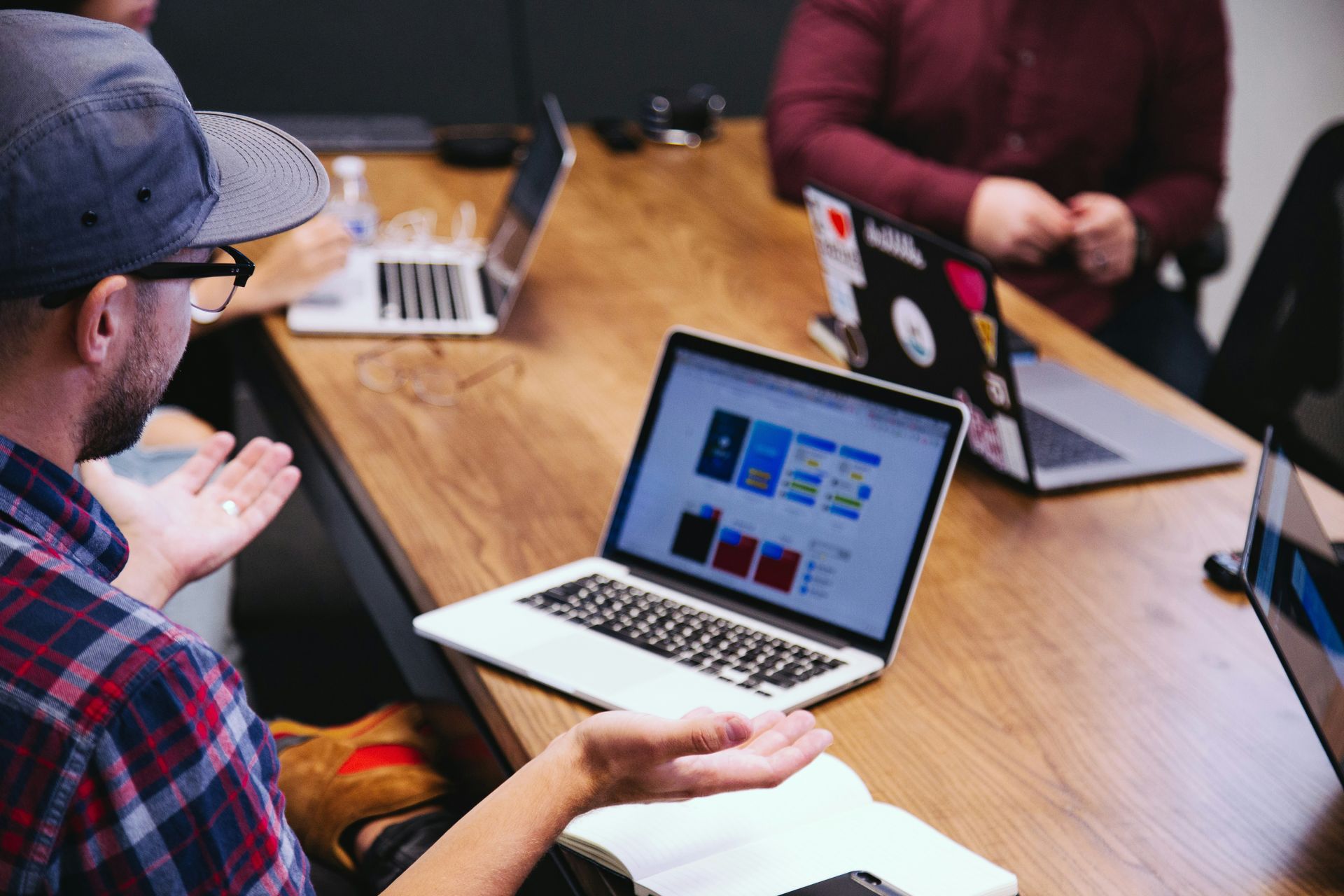 People in a meeting around a laptop on a wooden table, discussing a presentation