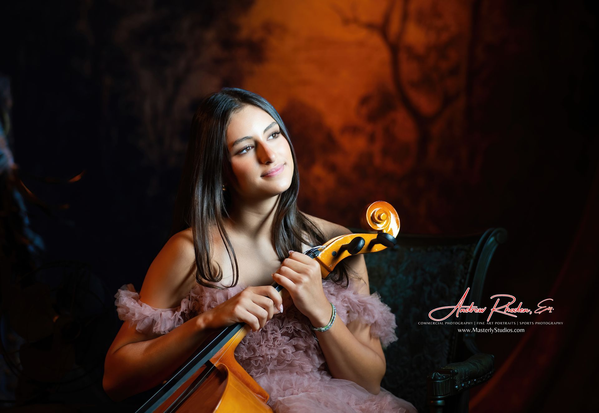 Woman in a pink dress holding a violin-like instrument against a dark orange backdrop