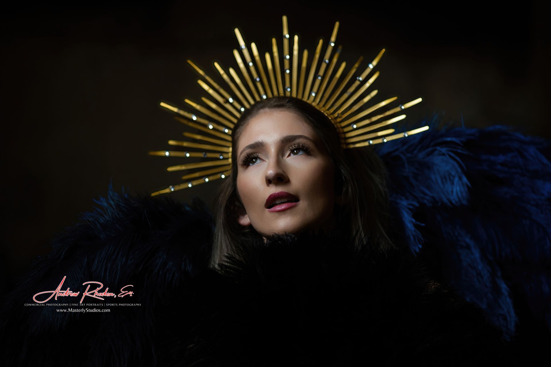 Woman in black with golden halo rays against a dark background, looking upward serenely